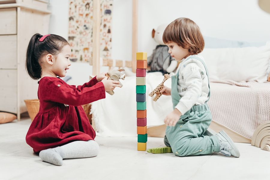 Two young children stacking colourful blocks
